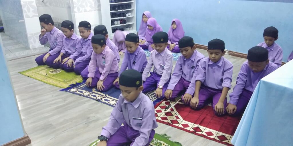 Murid sekolah rendah integrasi (SRI) Tahfiz Nadi Kingfisher sesi 2018 sedang solat zohor atau asar secara berjemaah.